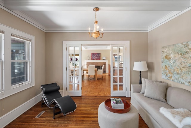 living area with an inviting chandelier, baseboards, ornamental molding, and dark wood-style flooring