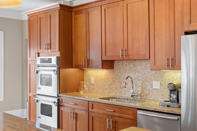 kitchen with a sink, appliances with stainless steel finishes, tasteful backsplash, and light stone counters