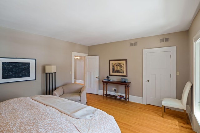 bedroom featuring baseboards, light wood-style flooring, and visible vents