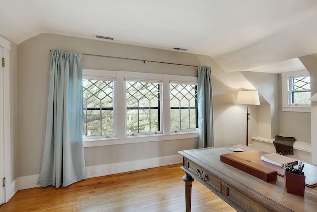 office area featuring baseboards, vaulted ceiling, light wood finished floors, and visible vents