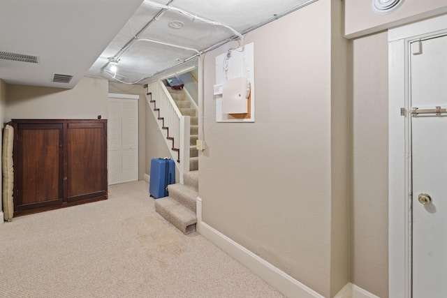 finished below grade area with carpet floors, baseboards, visible vents, and stairway