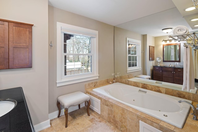 bathroom with a jetted tub, baseboards, and vanity