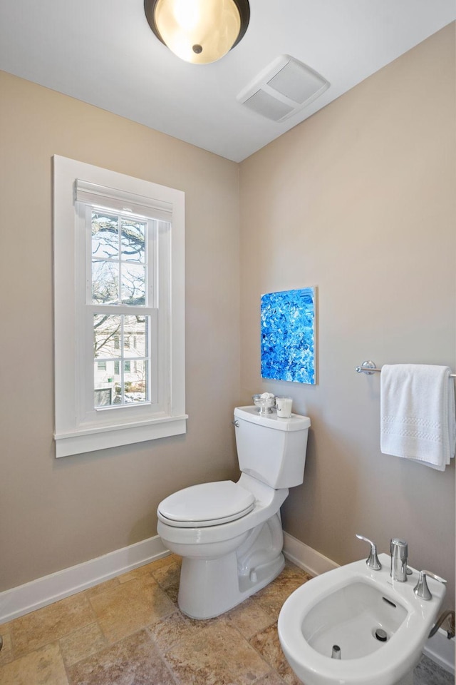 half bath featuring baseboards, toilet, a bidet, and visible vents