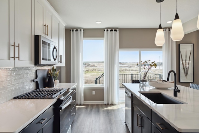 kitchen with stainless steel appliances, a sink, tasteful backsplash, light countertops, and dark wood-style flooring