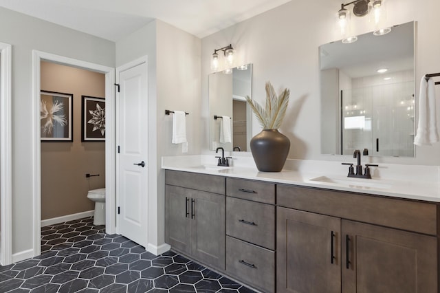 bathroom with double vanity, a shower stall, toilet, and baseboards