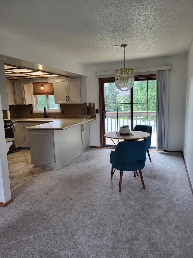 11620 Oregon Ave N, Champlin, MN 55316 - kitchen featuring a peninsula, gas stove, a textured ceiling, light carpet, and tasteful backsplash