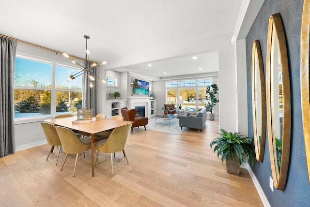 dining area featuring a textured ceiling, baseboards, light wood-style floors, and a chandelier