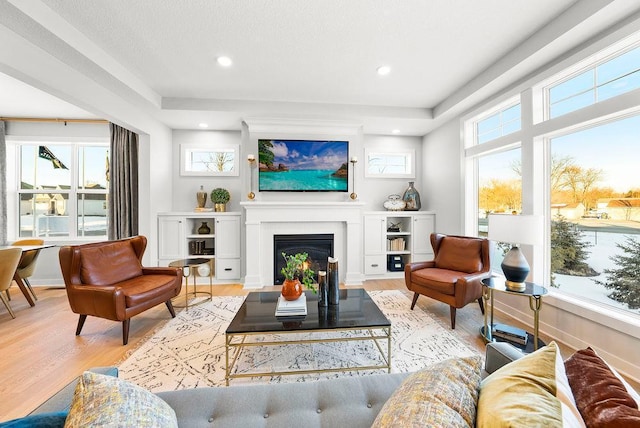 living area featuring recessed lighting, baseboards, a fireplace, and light wood-type flooring