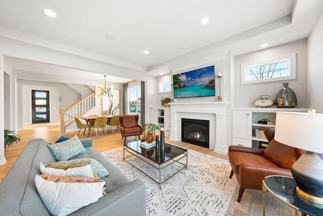 living room featuring light wood finished floors, stairs, and plenty of natural light
