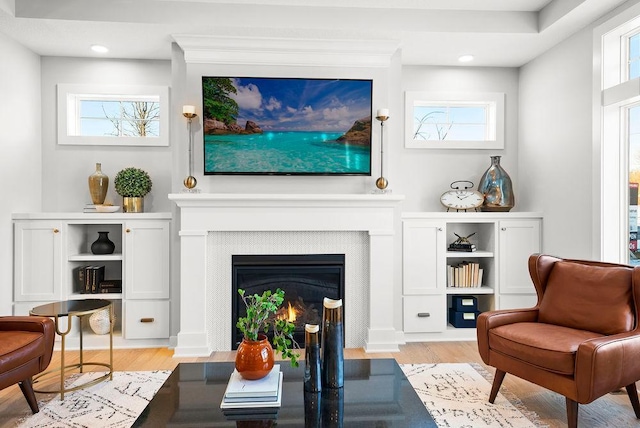 living area with a lit fireplace, light wood-style flooring, recessed lighting, and plenty of natural light