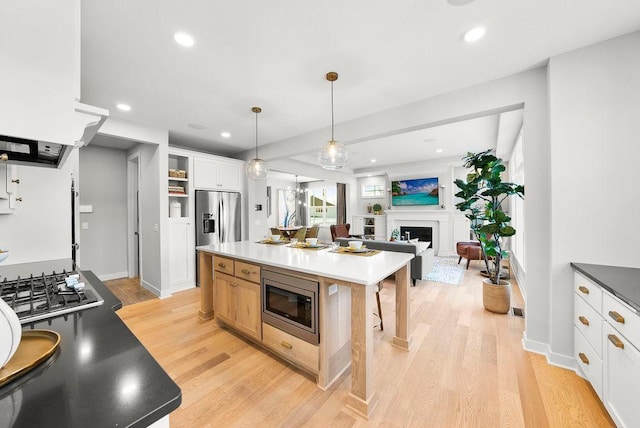 kitchen with a fireplace, stainless steel appliances, recessed lighting, and light wood-type flooring