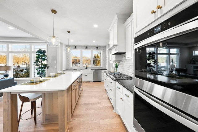 kitchen with a healthy amount of sunlight, light wood-style flooring, stainless steel appliances, and backsplash