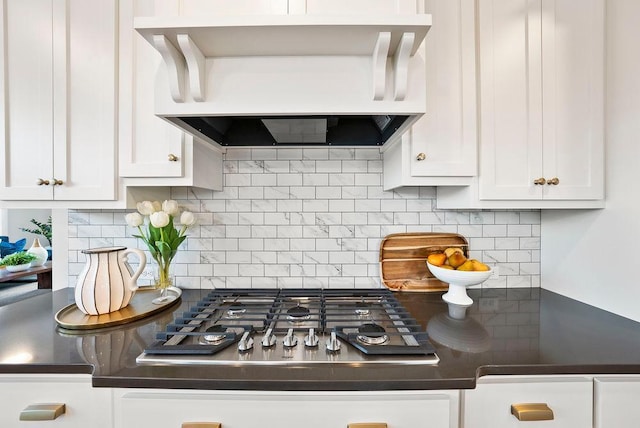 kitchen with wall chimney range hood, dark countertops, white cabinets, and stainless steel gas stovetop