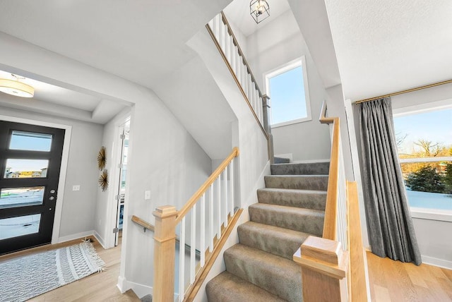 foyer entrance with stairs, wood finished floors, and baseboards