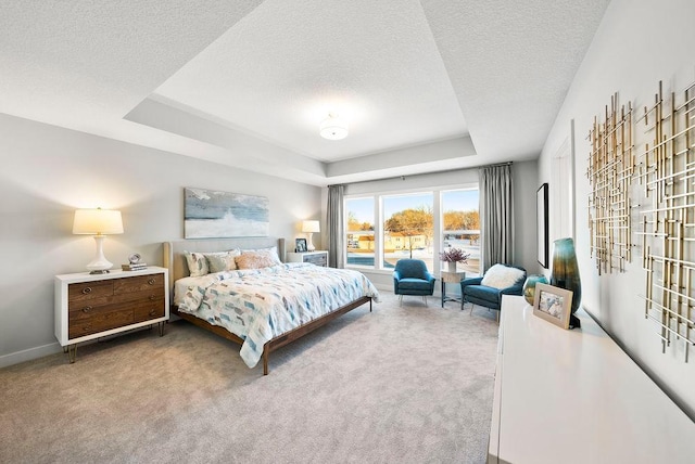 carpeted bedroom with a tray ceiling, baseboards, and a textured ceiling