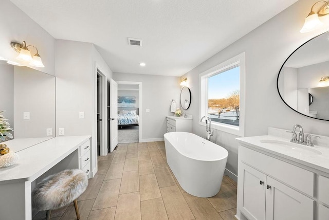 bathroom with vanity, a freestanding tub, baseboards, ensuite bath, and visible vents