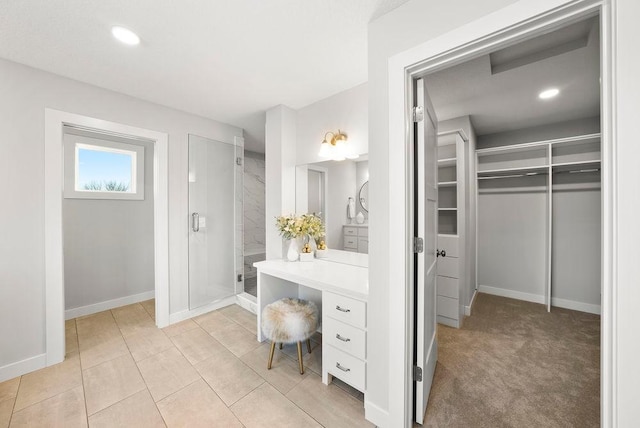 bathroom featuring a stall shower, vanity, a walk in closet, baseboards, and recessed lighting