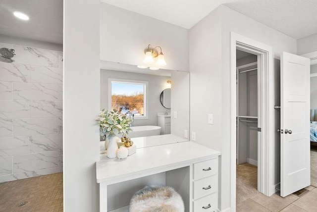 ensuite bathroom with vanity, a tile shower, stacked washer / drying machine, and ensuite bathroom