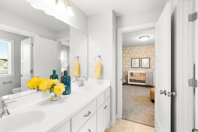 full bathroom featuring ensuite bathroom, double vanity, toilet, and a sink