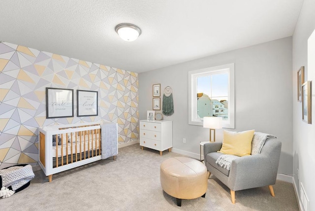 carpeted bedroom featuring baseboards, a textured ceiling, wallpapered walls, and an accent wall