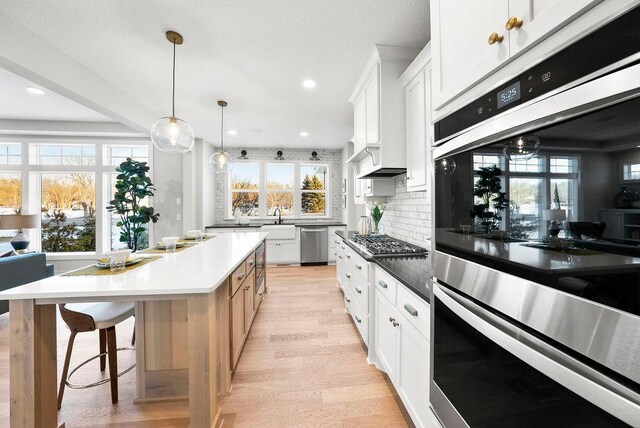 2712 Kensington Ave NE, Saint Michael, MN 55376 - kitchen with stainless steel appliances, light wood-style flooring, backsplash, a sink, and white cabinetry