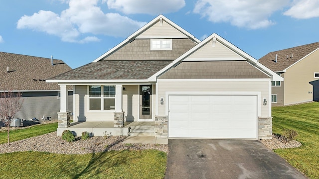 craftsman house featuring driveway, a front yard, an attached garage, and roof with shingles