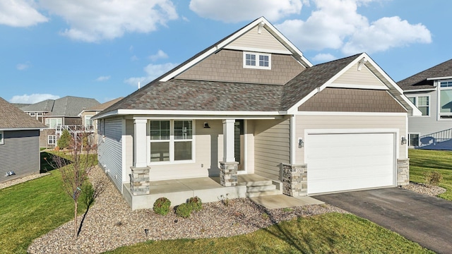 craftsman-style house featuring covered porch, driveway, a garage, and a front lawn