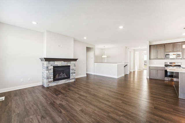 unfurnished living room with recessed lighting, a stone fireplace, baseboards, and dark wood finished floors