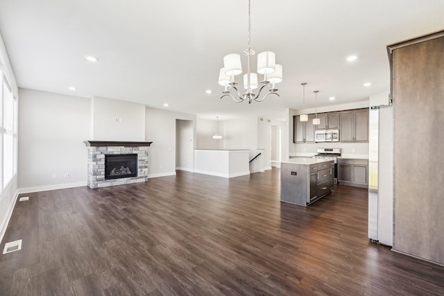 unfurnished living room featuring dark wood-style flooring, recessed lighting, a chandelier, and visible vents