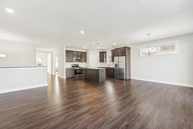 unfurnished living room featuring baseboards, dark wood-style flooring, recessed lighting, and a notable chandelier