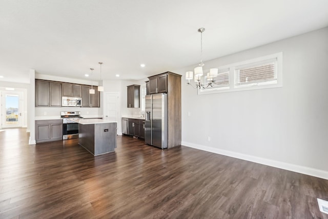 kitchen with dark brown cabinets, dark wood-style flooring, appliances with stainless steel finishes, and an inviting chandelier