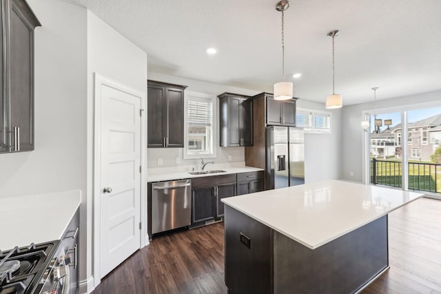 kitchen featuring light countertops, a sink, appliances with stainless steel finishes, and dark wood-type flooring
