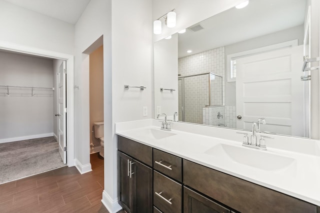 bathroom with a sink, toilet, a spacious closet, and a shower stall