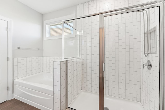full bathroom with wood finished floors, a stall shower, and a bath