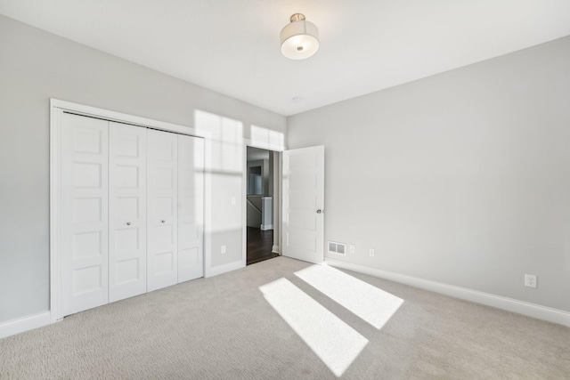 unfurnished bedroom with baseboards, carpet floors, visible vents, and a closet