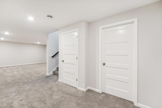 finished basement with baseboards, visible vents, stairs, and carpet