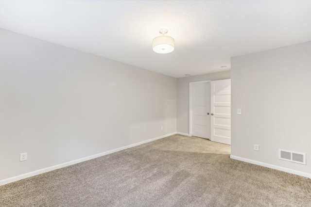 empty room featuring light colored carpet, visible vents, and baseboards