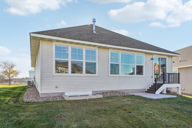 rear view of house with roof with shingles and a lawn