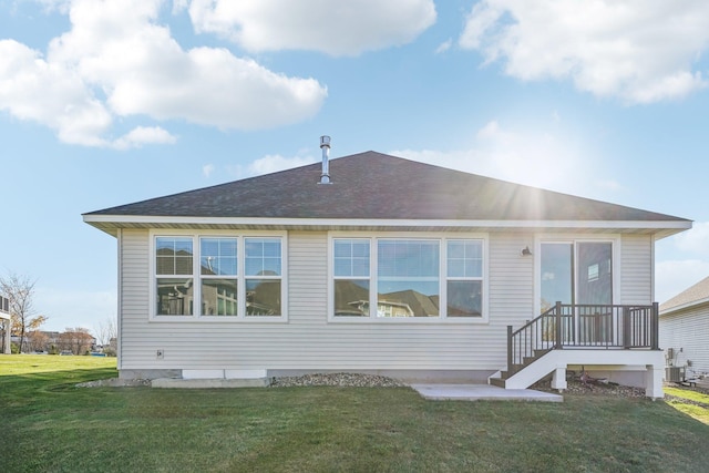 rear view of property with central AC, roof with shingles, and a yard