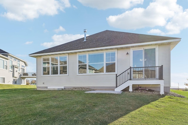 rear view of house with a lawn and roof with shingles