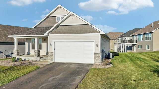view of front of house featuring stone siding, aphalt driveway, central AC, a front lawn, and a garage