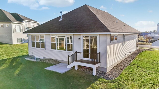 back of property with a shingled roof and a yard