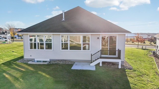 rear view of house featuring central AC unit and a yard