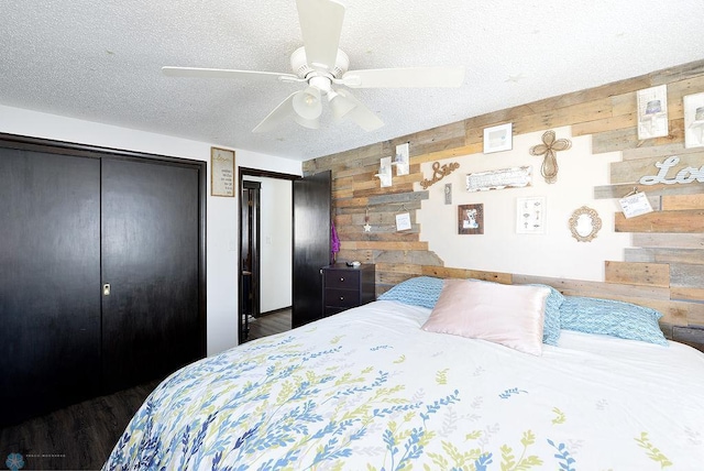 318 Morrison St, West Fargo, ND 58078 - bedroom featuring a textured ceiling, two closets, wood walls, ceiling fan, and wood finished floors