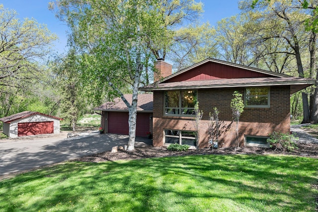 view of front of home featuring a chimney, brick siding, a front yard, driveway, and a garage