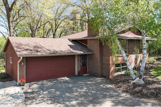 view of front of home featuring brick siding, a chimney, a shingled roof, a garage, and asphalt driveway