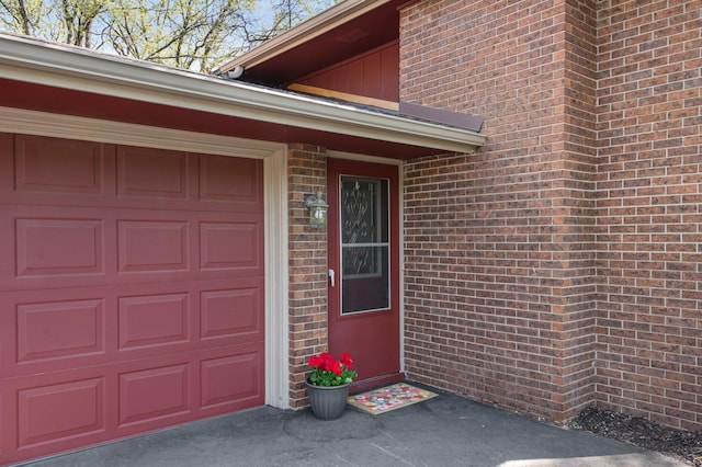 view of exterior entry featuring brick siding and an attached garage