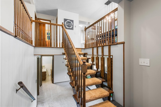 staircase with carpet floors and a high ceiling