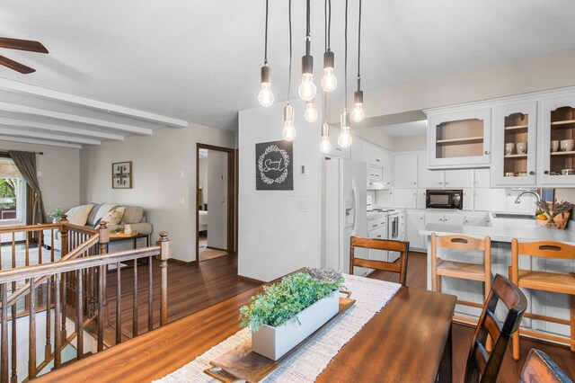 dining area with a ceiling fan, dark wood-style floors, and beam ceiling