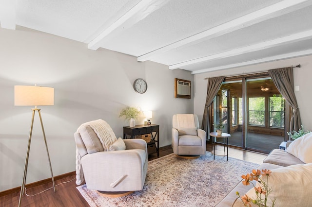 living room featuring beam ceiling, a textured ceiling, wood finished floors, a wall mounted air conditioner, and baseboards